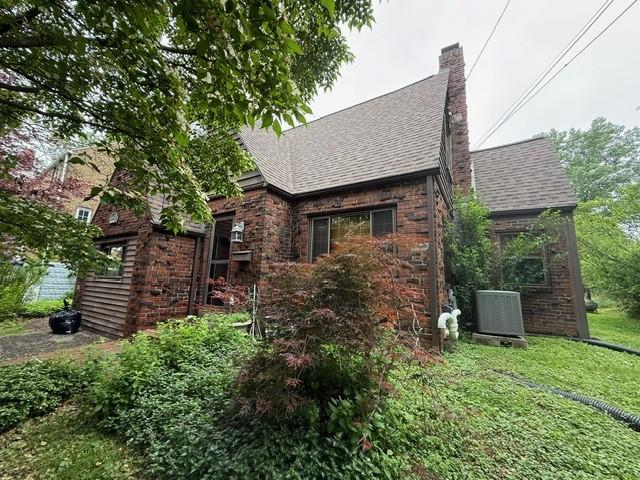 5524 Zieger Ave, Penn Hills, PA 15147 - back of property featuring a chimney, brick siding, a shingled roof, and a yard