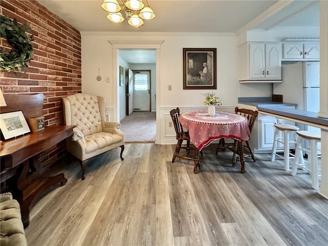 240 Reed St, Lower Burrell, PA 15068 - dining space with a chandelier, light wood-style flooring, ornamental molding, brick wall, and a wainscoted wall