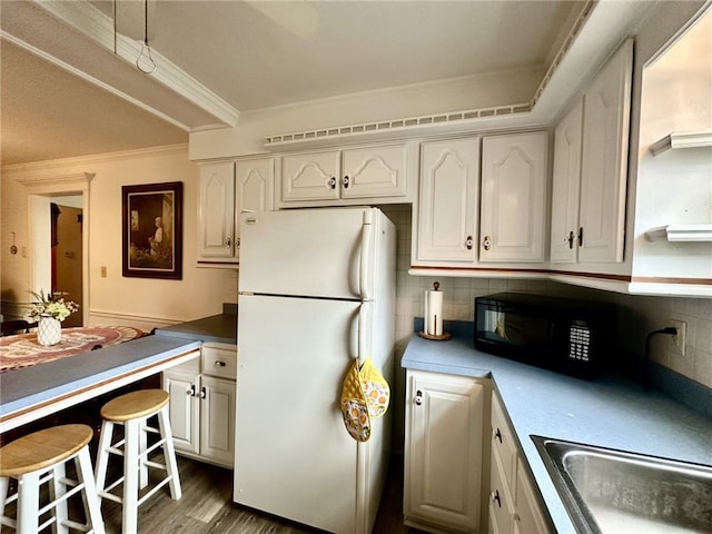 240 Reed St, Lower Burrell, PA 15068 - kitchen featuring freestanding refrigerator, black microwave, white cabinetry, ornamental molding, and tasteful backsplash