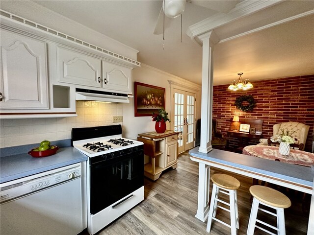 240 Reed St, Lower Burrell, PA 15068 - kitchen with white appliances, under cabinet range hood, white cabinetry, light wood finished floors, and decorative backsplash