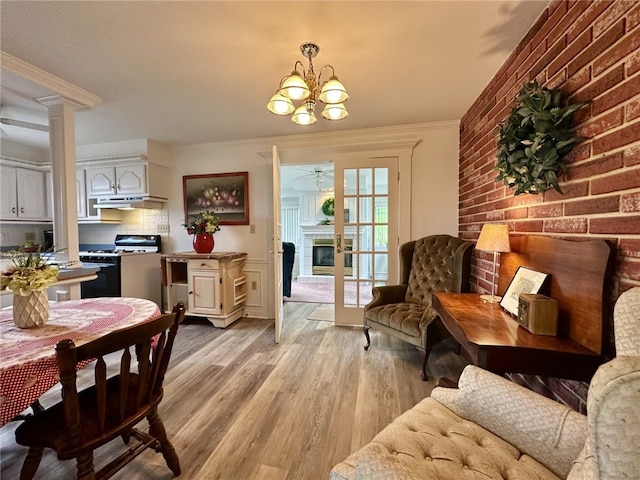 240 Reed St, Lower Burrell, PA 15068 - dining room with a chandelier, light wood finished floors, a fireplace, a ceiling fan, and brick wall