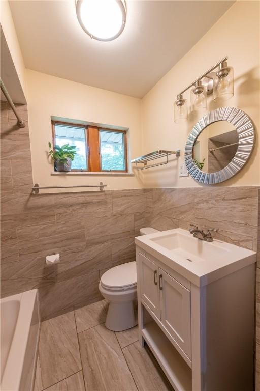 670 Lougeay Rd, Penn Hills, PA 15235 - full bathroom featuring tile walls, vanity, and a wainscoted wall