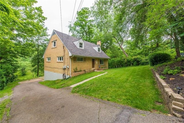 670 Lougeay Rd, Penn Hills, PA 15235 - cape cod house with a chimney, a front yard, brick siding, and a shingled roof