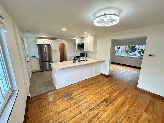 7207 Mcclure Ave, Swissvale, PA 15218 - kitchen featuring appliances with stainless steel finishes, a peninsula, light wood finished floors, white cabinetry, and recessed lighting