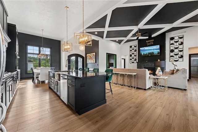 7858 Oscar Ct, North Huntingdon, PA 15642 - kitchen with a chandelier, a warm lit fireplace, wood finished floors, dark cabinetry, and a kitchen bar