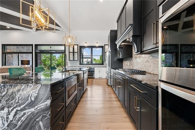 7858 Oscar Ct, North Huntingdon, PA 15642 - kitchen featuring appliances with stainless steel finishes, dark stone countertops, backsplash, dark cabinets, and beam ceiling