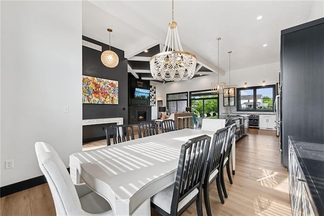 7858 Oscar Ct, North Huntingdon, PA 15642 - dining room with a chandelier, wine cooler, beam ceiling, light wood-style flooring, and a lit fireplace