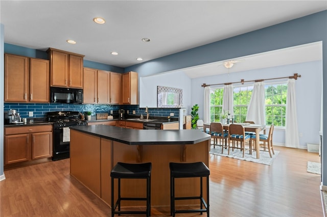 161 Buckingham Dr, Ohio Twp, PA 15237 - kitchen featuring black appliances, tasteful backsplash, light wood-type flooring, dark countertops, and a breakfast bar area