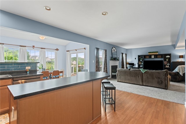 161 Buckingham Dr, Ohio Twp, PA 15237 - kitchen featuring dark countertops, a glass covered fireplace, light wood finished floors, a kitchen breakfast bar, and stainless steel dishwasher
