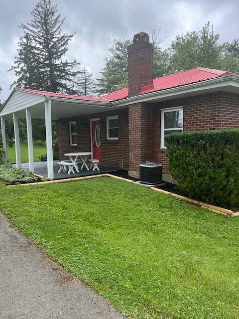 82 Crossridge, Crossridge, PA 15022 - rear view of property with brick siding, a lawn, a chimney, and a metal roof