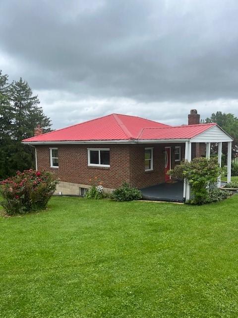 82 Crossridge, Crossridge, PA 15022 - back of property with brick siding, a metal roof, a yard, and a chimney