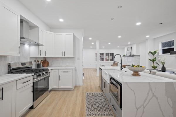 2356 Pittock St, Squirrel Hill, PA 15217 - kitchen featuring appliances with stainless steel finishes, light wood-style flooring, wall chimney range hood, white cabinets, and recessed lighting