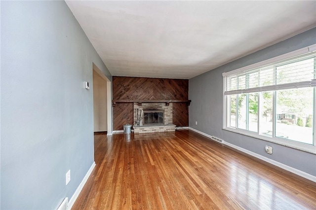 215 Columbia Dr, Center Twp Bea, PA 15001 - unfurnished living room with wood finished floors, a brick fireplace, and wood walls