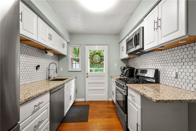 828 Oranmore St, Stanton Heights, PA 15201 - kitchen featuring appliances with stainless steel finishes, decorative backsplash, white cabinets, and light wood finished floors