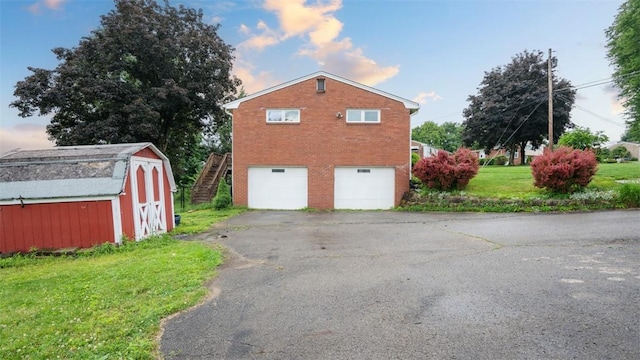 108 Tanglewood Dr, Middlesex Twp, PA 16059 - view of property exterior with a garage, a storage unit, asphalt driveway, brick siding, and a lawn