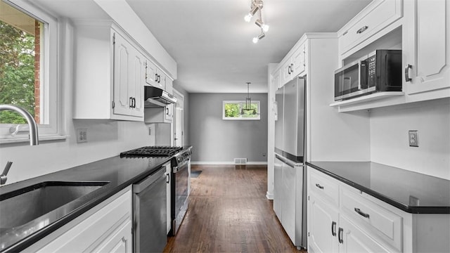 108 Tanglewood Dr, Middlesex Twp, PA 16059 - kitchen with appliances with stainless steel finishes, under cabinet range hood, dark countertops, dark wood-style flooring, and white cabinets