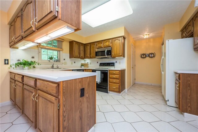 221 William Dr, North Strabane, PA 15317 - kitchen with electric range oven, stainless steel microwave, freestanding refrigerator, a peninsula, and brown cabinetry