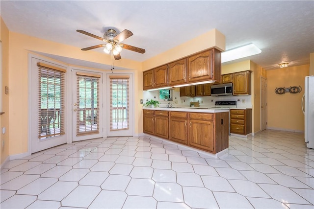 221 William Dr, North Strabane, PA 15317 - kitchen featuring stainless steel microwave, freestanding refrigerator, light countertops, brown cabinets, and ceiling fan