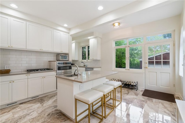 1463 Beechwood Blvd, Squirrel Hill, PA 15217 - kitchen featuring appliances with stainless steel finishes, backsplash, white cabinets, a kitchen breakfast bar, and light countertops