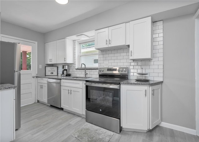 1709 Main St, Aliquippa, PA 15001 - kitchen featuring appliances with stainless steel finishes, light stone counters, white cabinetry, tasteful backsplash, and light wood finished floors