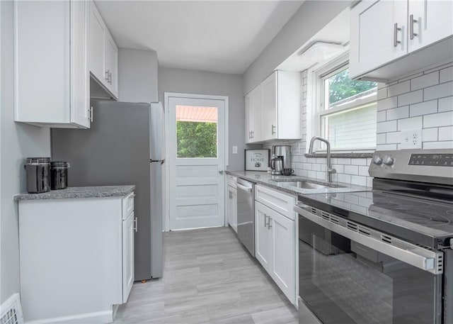 1709 Main St, Aliquippa, PA 15001 - kitchen featuring appliances with stainless steel finishes, white cabinets, backsplash, light stone countertops, and light wood-style floors