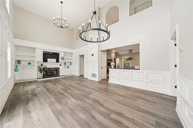 11 Sunset Ct, Cranberry Twp, PA 16066 - unfurnished living room featuring a high ceiling, a chandelier, a decorative wall, wood finished floors, and a wainscoted wall