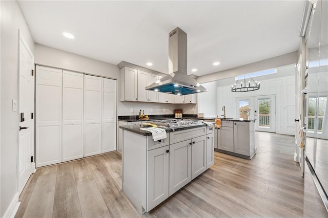 11 Sunset Ct, Cranberry Twp, PA 16066 - kitchen featuring island exhaust hood, a center island, stainless steel gas stovetop, dark countertops, and gray cabinetry