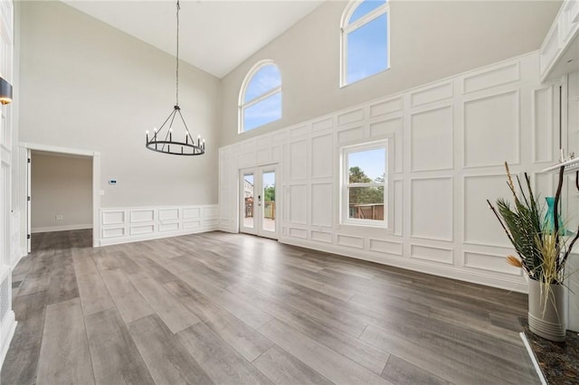 11 Sunset Ct, Cranberry Twp, PA 16066 - unfurnished living room with a decorative wall, high vaulted ceiling, a chandelier, wood finished floors, and french doors