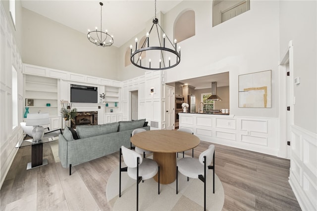 11 Sunset Ct, Cranberry Twp, PA 16066 - dining area featuring a high ceiling, a chandelier, a decorative wall, light wood-type flooring, and a wainscoted wall