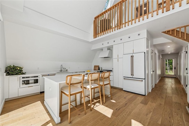 3019 Oak Ridge Ln, Saltlick Twp, PA 15622 - kitchen with white appliances, light wood-style floors, vaulted ceiling, a kitchen island, and exhaust hood