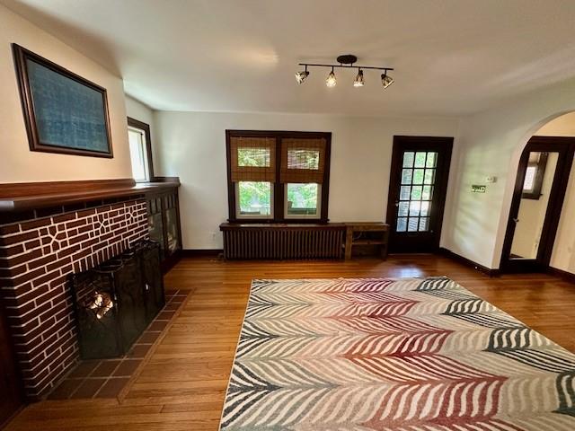 111 Race St, Regent Square, PA 15218 - living room featuring radiator, arched walkways, wood finished floors, and a tile fireplace