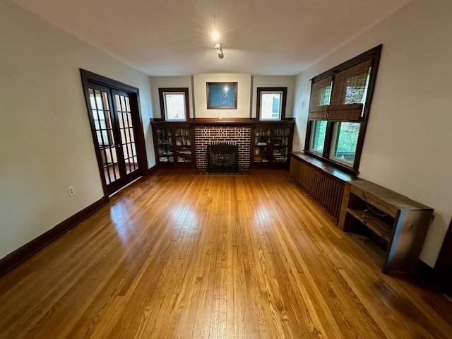 111 Race St, Edgewood, PA 15218 - unfurnished living room with wood finished floors, a brick fireplace, and radiator
