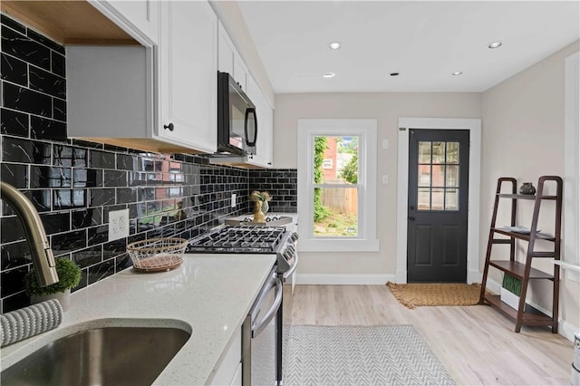 927 Greenfield Ave, Greenfield, PA 15217 - kitchen with appliances with stainless steel finishes, light wood-style flooring, tasteful backsplash, white cabinetry, and recessed lighting
