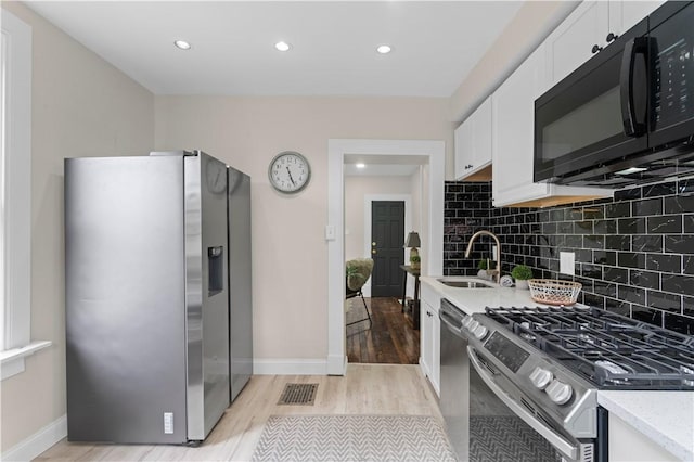 927 Greenfield Ave, Greenfield, PA 15217 - kitchen with appliances with stainless steel finishes, light wood finished floors, white cabinetry, tasteful backsplash, and recessed lighting