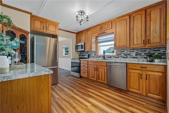 1072 Aetna Dr, Wayne Twp Law, PA 16117 - kitchen featuring stainless steel appliances, light wood finished floors, crown molding, tasteful backsplash, and brown cabinets