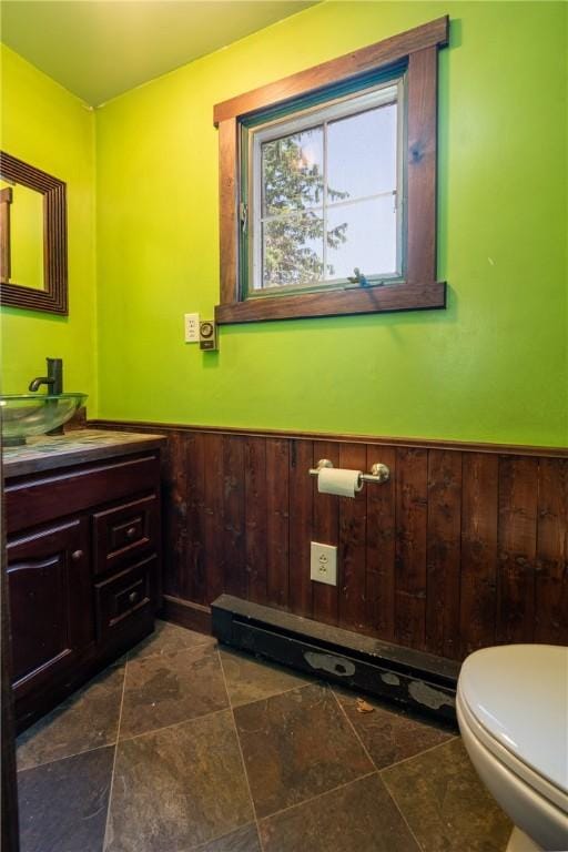 4177 Main St, Cook Twp, PA 15687 - bathroom featuring vanity, a wainscoted wall, wood walls, a baseboard radiator, and stone finish floors