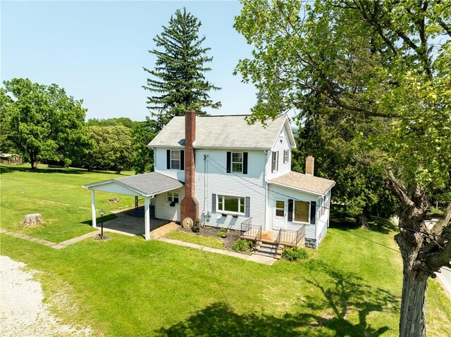 4177 Main St, Cook Twp, PA 15687 - rear view of house featuring a chimney, driveway, a lawn, roof with shingles, and an attached carport