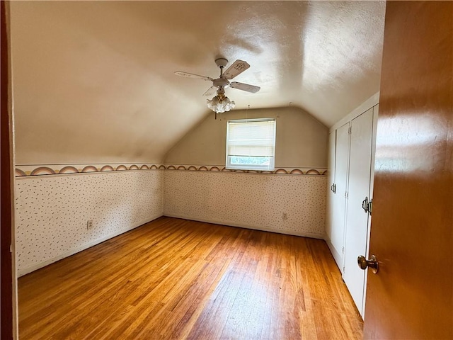 1320 Main St, Bridgeville, PA 15017 - additional living space featuring light wood-type flooring, a ceiling fan, lofted ceiling, wallpapered walls, and a textured ceiling