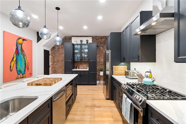 161 Morewood, Oakland, PA 15213 - kitchen featuring appliances with stainless steel finishes, wall chimney exhaust hood, light wood finished floors, glass insert cabinets, and pendant lighting