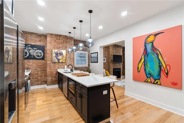 161 Morewood, Oakland, PA 15213 - kitchen with stainless steel appliances, a kitchen bar, brick wall, a fireplace, and light wood finished floors