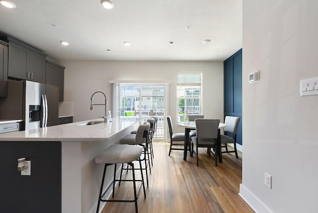 1408 Commons Ln, South Fayette, PA 15017 - kitchen with stainless steel refrigerator with ice dispenser, a kitchen bar, light wood-type flooring, a center island with sink, and recessed lighting