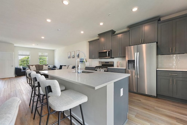 1408 Commons Ln, South Fayette, PA 15017 - kitchen with stainless steel appliances, a breakfast bar, a center island with sink, recessed lighting, and light wood-type flooring