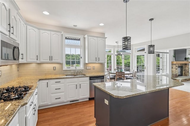 203 Cashmere Ct, Cranberry Twp, PA 16066 - kitchen with stainless steel appliances, light wood-style flooring, white cabinetry, hanging light fixtures, and tasteful backsplash