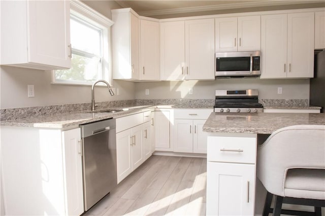 132 Hidden Acres Dr, Forward Twp, PA 16033 - kitchen featuring appliances with stainless steel finishes, white cabinetry, light wood-style flooring, light stone counters, and ornamental molding
