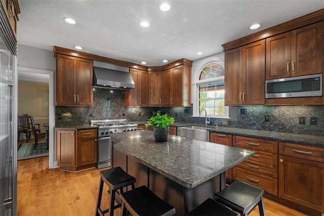 116 Bunker Hill Dr, Peters Twp, PA 15317 - kitchen featuring high quality appliances, wall chimney exhaust hood, a breakfast bar area, light wood-style floors, and recessed lighting