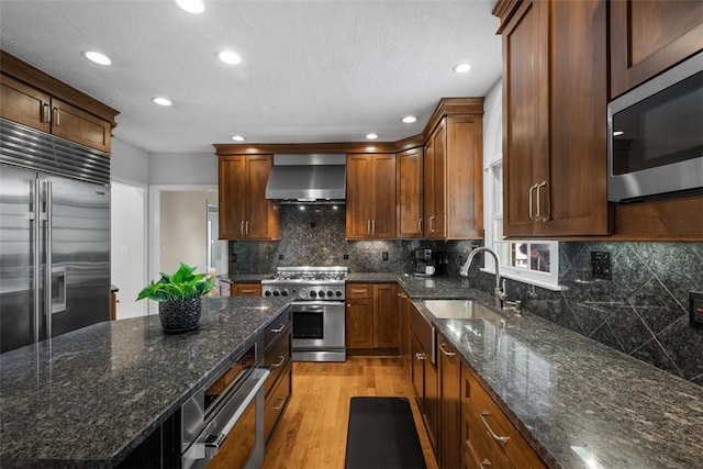 116 Bunker Hill Dr, Peters Twp, PA 15317 - kitchen featuring wall chimney exhaust hood, high quality appliances, light wood-type flooring, recessed lighting, and dark stone countertops