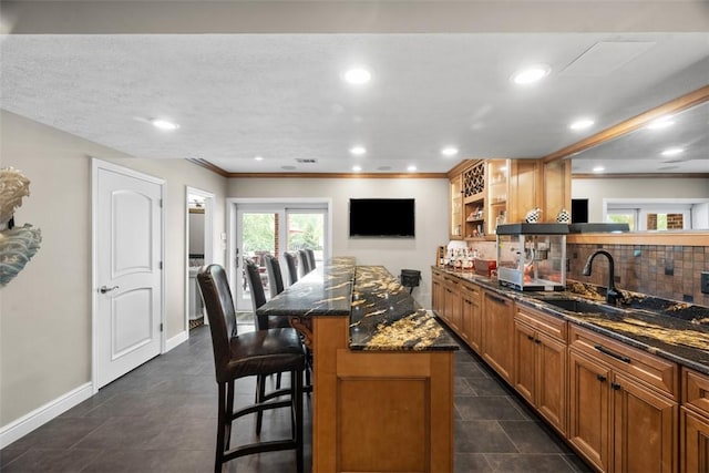 116 Bunker Hill Dr, Peters Twp, PA 15317 - kitchen with a kitchen breakfast bar, dark stone counters, tasteful backsplash, brown cabinetry, and a kitchen island