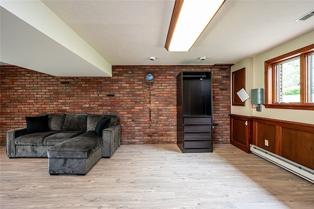 317 Bridlewood Dr, Hempfield Twp Wml, PA 15601 - living room featuring baseboard heating, light wood-style floors, a wainscoted wall, brick wall, and a textured ceiling