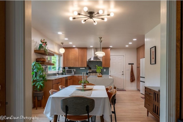 8 Windycrest Dr, Patterson Twp, PA 15010 - kitchen with stainless steel appliances, wall chimney range hood, a chandelier, light wood finished floors, and brown cabinetry