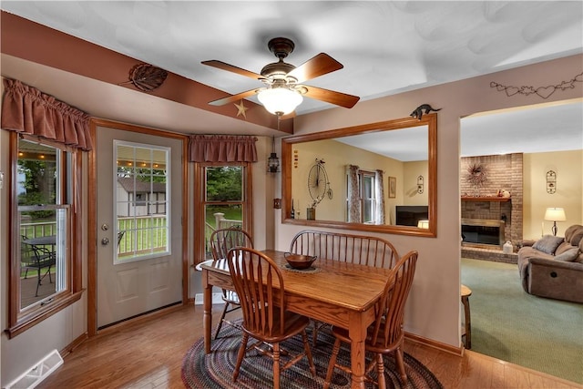 108 Birchwood Way, Penn Twp Wml, PA 15642 - dining area featuring a brick fireplace, a ceiling fan, and wood finished floors